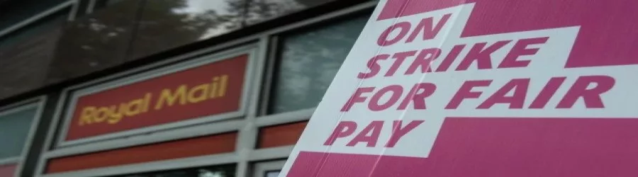 An image containing the Royal Mail logo and a sign about striking for fair pay